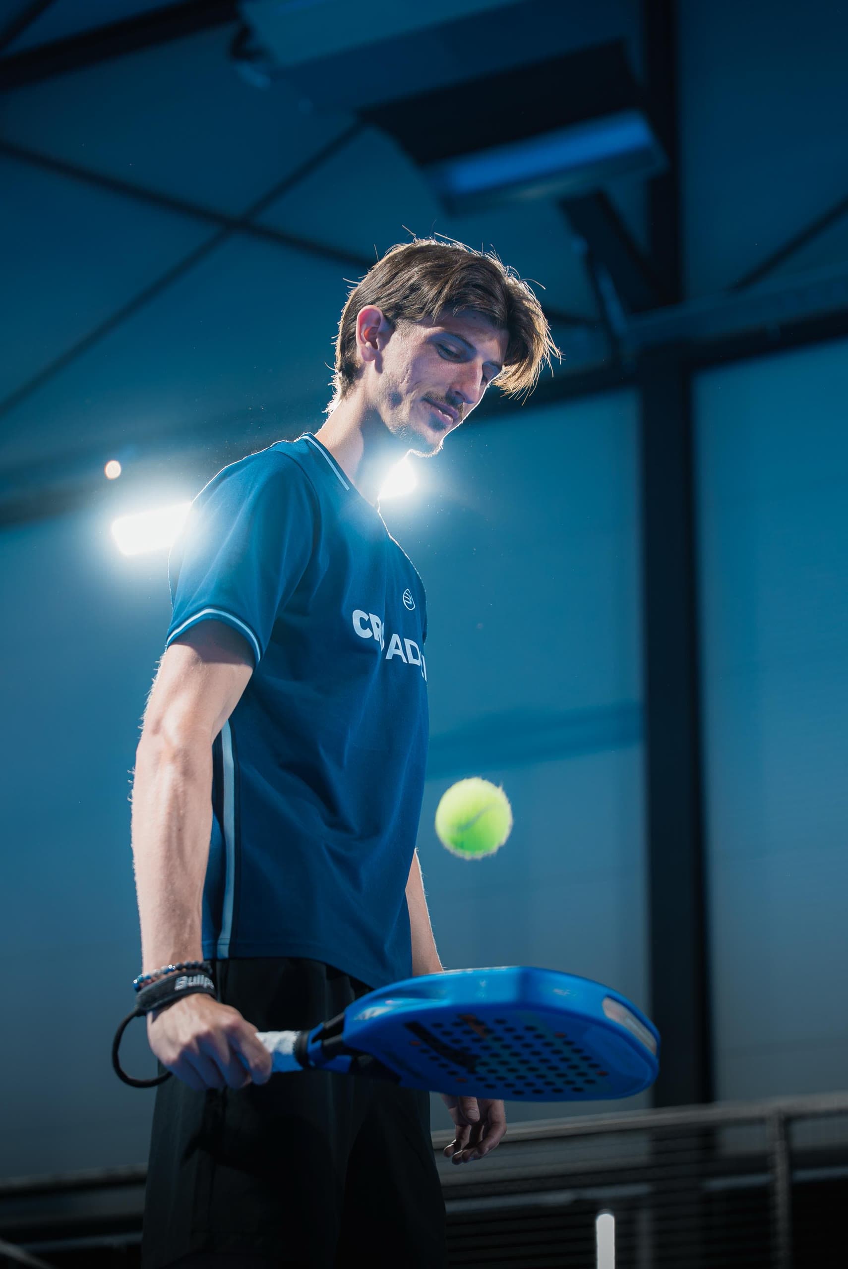 Ahmed Musić with a blue padel racket and a yellow ball on court